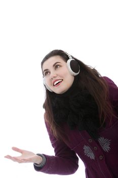 Young attractive woman wearing ear muffs holding her hand out looking towards the sky.