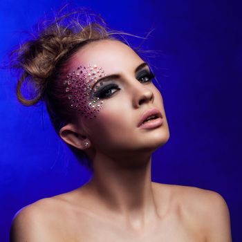 Beautiful woman with fantasy makeup on a blue background