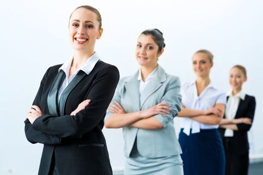 group of business people standing in a row, smiling and crossing his arms