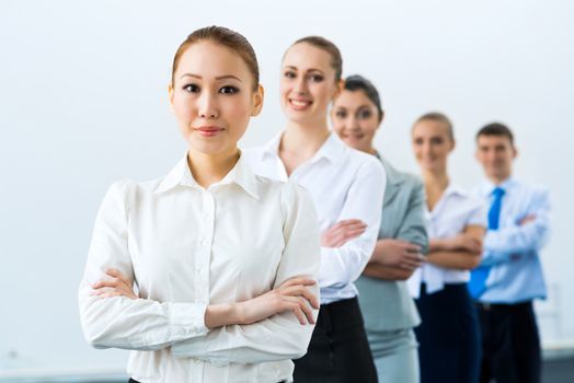 group of business people standing in a row, smiling and crossing his arms