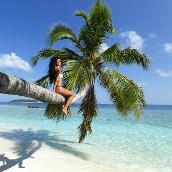 Beautiful woman sitting on palm on sea background