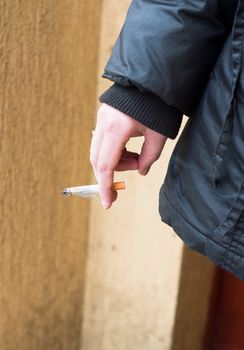 Girl holding cigarette in jacket