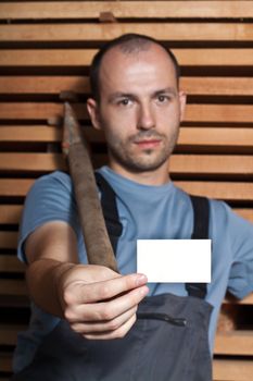 Craftsman with a big hammer holding a business card on wooden background