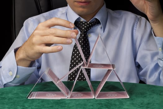 A businessman trying to build a tower of cards, but fails.