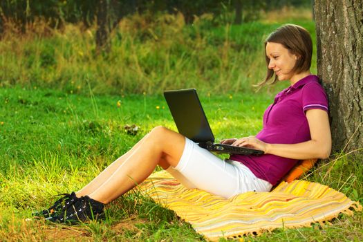 Beautiful excited woman with a laptop in the park