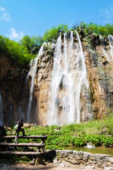 Young female tourist shooting a waterfal. Shot at Plitvice lakes national park, Croatia.