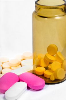 Medicine bottle with purple and yellow pills against white isolated background