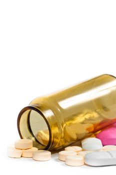 Medicine bottle with purple and yellow pills against white isolated background