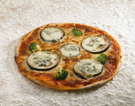 A tasty pizza eggplant on a bed of flour.