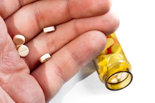 Hand of a man holding pills with medicine on background