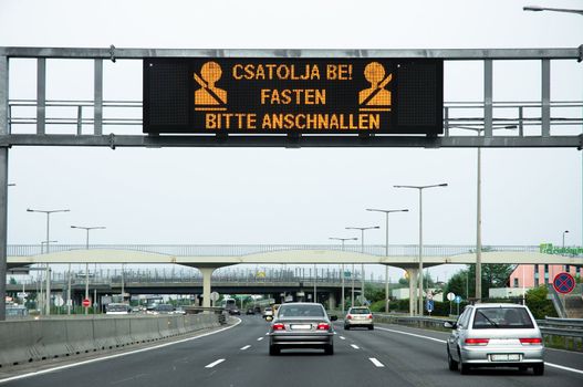 Warning sign on highway with some cars on the road