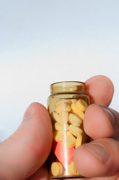 Hand holding medicine bottle full of pills