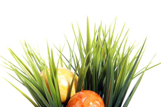 Two colourful marble pattern painted Easter Eggs in orange and yellow hidden in fresh green spring grass isolated on white