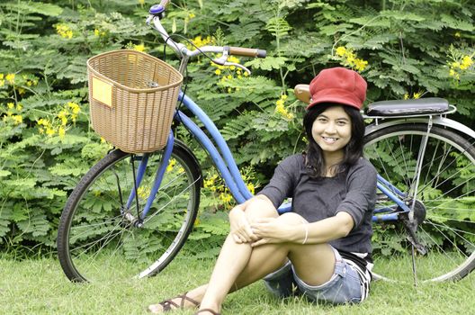 Beautiful girl with a bicycle rests on a grass