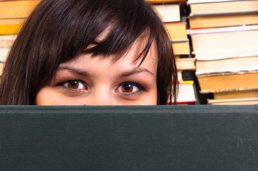 Girl hiding behind book with blurry background
