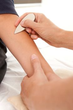 Young male acupuncture patient receiving Shonishin treatment with a chokishin tool