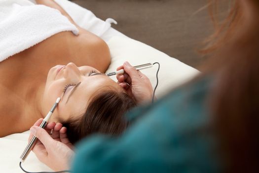 Attractive female patient receiving electro acupuncture on face as part of a anti-aging beauty treatment