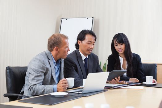 Businesspeople discussing while looking at electronic tablet