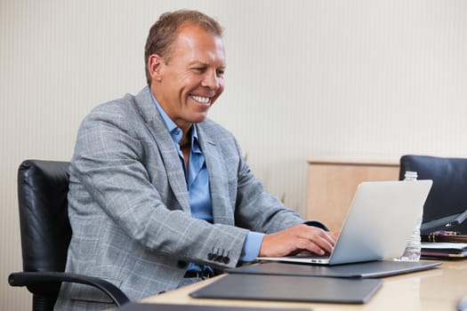 Smiling businessman working on laptop in an office