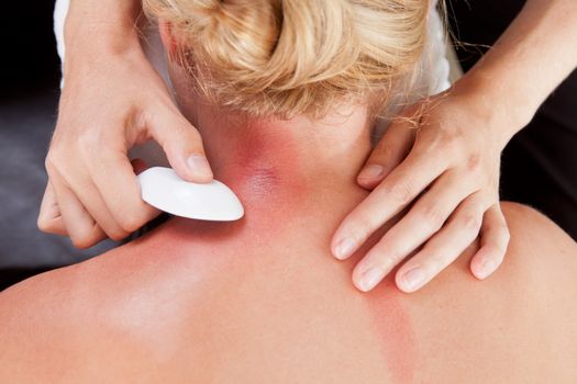 Above view of woman receiving gua-sha treatment on back and neck
