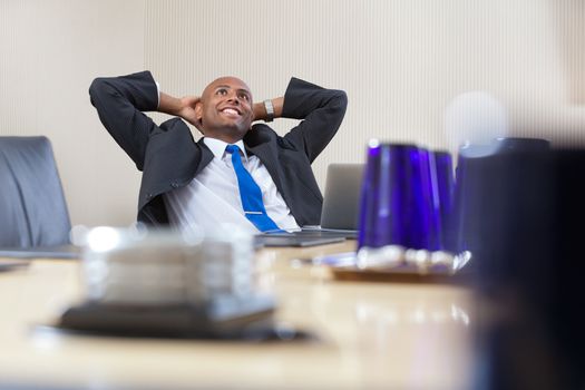 Relaxed executive daydreaming with hands on back of head