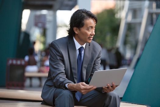 Businessman holding laptop and looking away