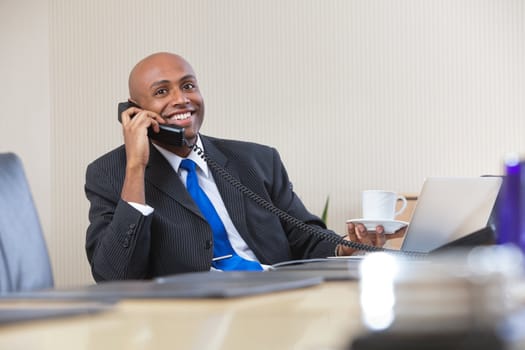 Portrait of Afro American businessman talking on telephone while holding cup of tea