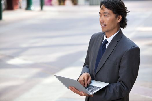 Handsome businessman using laptop outdoors