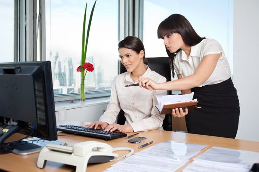 Two female business women in office setting working