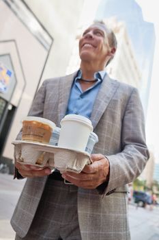 Smiling businessman holding takeaway coffee cups
