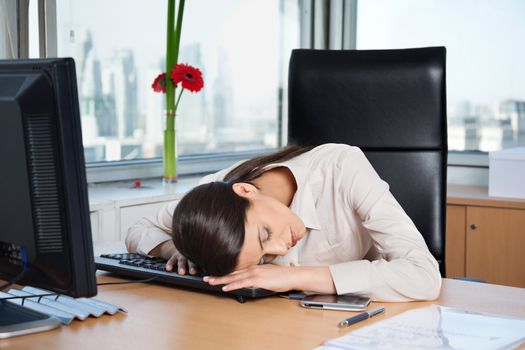 Tired business woman sleeping on the keyboard in office