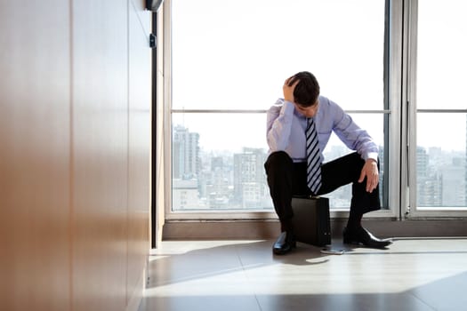 Young business man sitting in depression with hand on head