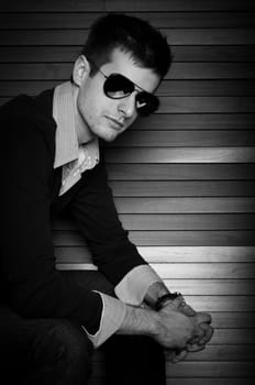 Young man sitting in the window with sunglasses in black and white