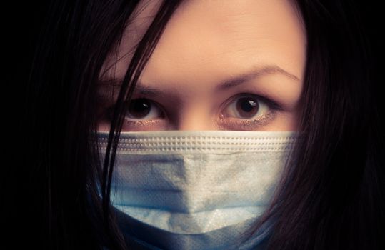 Girl in protective mask against dark background