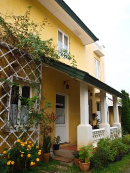 Two storey yellow house and porch with garden in nature