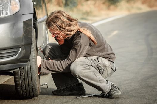 Young man repairing car outdoors sitting