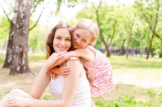 mother and daughter sitting together on the grass, and spend time with family