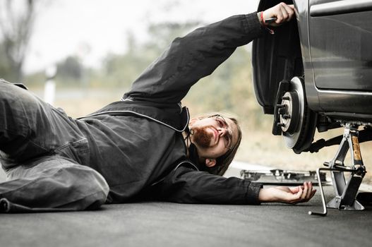 Handsome young man repairing car