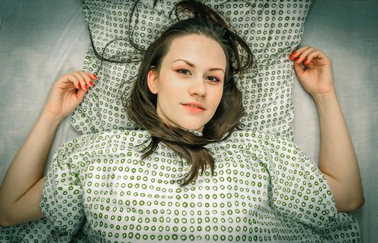 Young woman in the bed in bright light