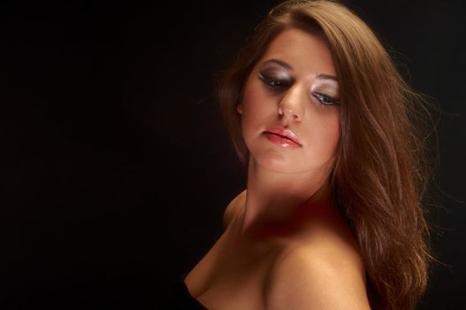 Girl with long hair in the studio against dark background