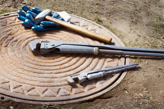 Hammer and wrench are on a rusty manhole