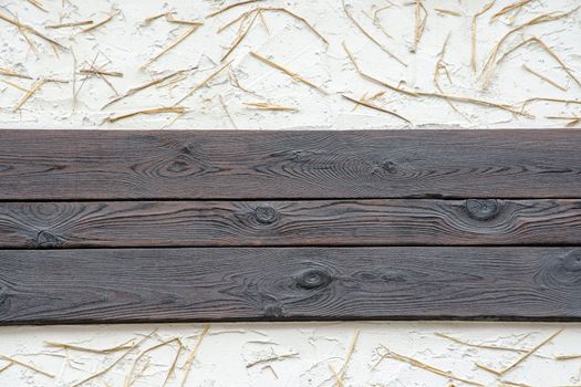 A background of a wall with black planks, white plaster and straw