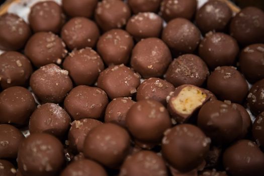 Chocolate candies of different shapes and broken pieces of chocolate. Delicious food background. Selective focus on the candies