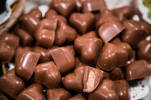 Chocolate candies of different shapes and broken pieces of chocolate. Delicious food background. Selective focus on the candies