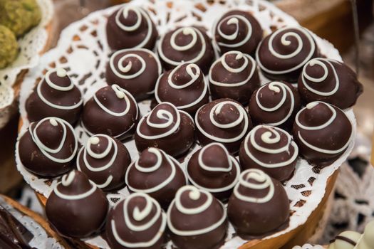 Chocolate candies of different shapes and broken pieces of chocolate. Delicious food background. Selective focus on the candies