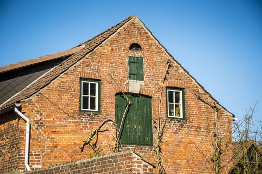 Front view of a red brick house with trees and blue sky