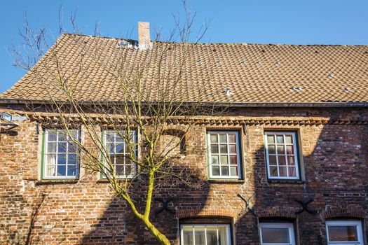 Side view of a red brick house with trees and blue sky