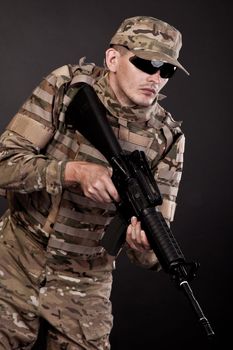 Modern soldier with rifle isolated on a black background