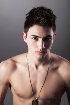 A good looking, muscular built, man on a black background with dog tags.