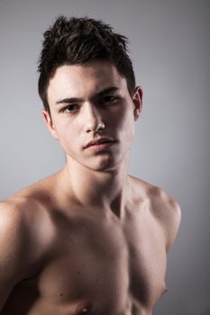 Handsome face of a young man. Isolated on grey background.